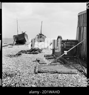 Dungeness, Lydd, Shepway, Kent. Un treuil à bateau et des bateaux à proximité sur la plage de Dungeness. Banque D'Images