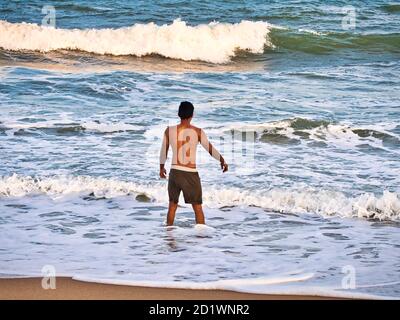 PUDUCHERRY, INDE - DÉCEMBRE CIRCA, 2018. Silhouette masculine non identifiée dans l'eau de mer sur une plage de sable. Jeune garçon adulte sur la plage - magnifique dos Banque D'Images