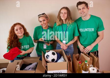 jeunes volontaires enthousiastes avec des dons pour les pauvres, boîte en carton avec des vêtements pour la charité. les gens gentils aident les pauvres, des étuis pleins de vêtements pour les pauvres dons, concept d'activité sociale Banque D'Images