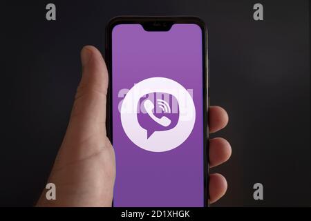 L'écran d'un smartphone tenu par une main masculine Avec le logo de l'application de visioconférence Viber Messenger sur un noir arrière-plan Banque D'Images