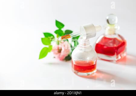 Bouteille d'huile essentielle de rose et fleurs sur fond blanc. Concept de massage, d'aromathérapie et de cosmétiques biologiques. Banque D'Images