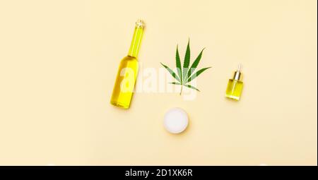 Produit cosmétique avec de l'huile de cannabis sur fond de couleur chameau. Crème, huile de CBD, huile essentielle feuilles de cannabis. Espace de copie de la bannière Web longue à plat Banque D'Images