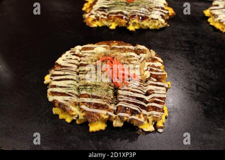 Okonomiyaki la pizza dite japonaise est cuite sur la casserole ou le teppan. Banque D'Images