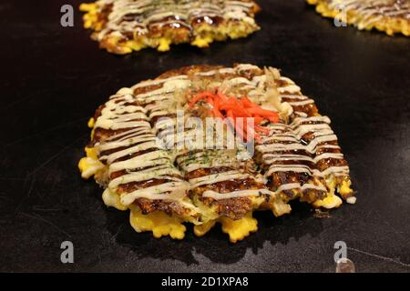 Okonomiyaki la pizza dite japonaise est cuite sur la casserole ou le teppan. Banque D'Images