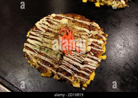 Okonomiyaki la pizza dite japonaise est cuite sur la casserole ou le teppan. Banque D'Images