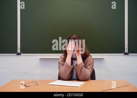 Triste professeur assis dans une salle de classe d'école, espace de copie Banque D'Images