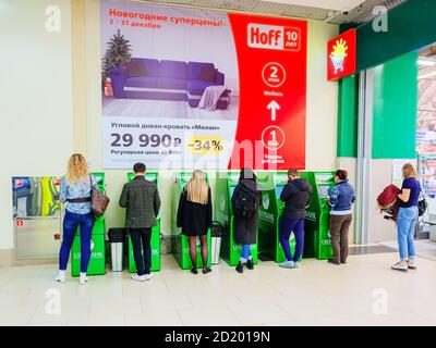 Sotchi, Russie - 14 décembre 2019. Les gens se tiennent à des guichets automatiques verts contre le fond de mur avec une grande bannière publicitaire Banque D'Images