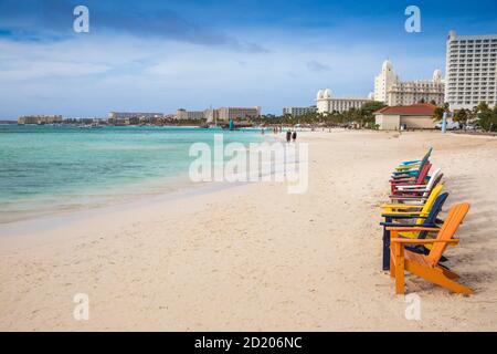 Aruba, UNE rangée de chaises longues en bois colorées sur Palm Beach Banque D'Images
