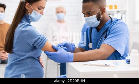 Femme enceinte dans le masque recevant l'injection du vaccin contre le coronavirus à l'hôpital Banque D'Images