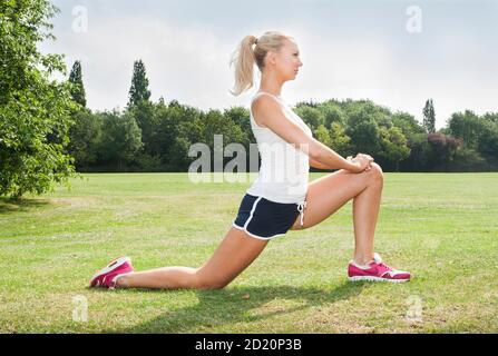 Jeune blonde blanche femme dans sa fin 20s - 30s portant des vêtements d'athlétisme pour faire des exercices d'étirement. Banque D'Images