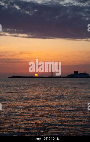 Magnifique ciel nocturne derrière le phare brillant. Coucher de soleil dans la mer a Banque D'Images