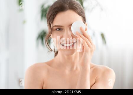Joyeuse jeune femme enlever le maquillage de ses yeux Banque D'Images