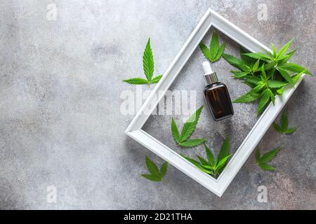 Composition de produits cosmétiques de chanvre dans un pot et feuilles vertes de plantes sur fond blanc de table en bois. Cosmétiques naturels. Huile CBD pour cosmétiques. Banque D'Images