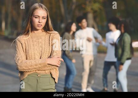 Frustré blondy fille debout sur le groupe d'adolescents Banque D'Images