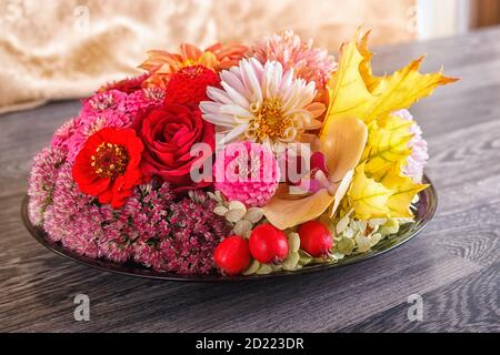 arrangement floral de fleurs d'automne sur une assiette. dahlia, zinnia, rose, orchidée, feuilles d'érable. Banque D'Images