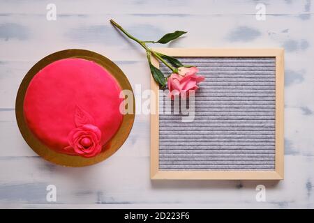 Gâteau rouge recouvert de marzepan ou de mastic avec une fleur sur fond blanc, espace de copie Banque D'Images