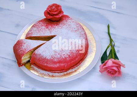 Gâteau rouge recouvert de massepain ou de mastic coupé et arrosé de sucre blanc en poudre Banque D'Images