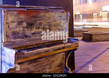 Un vieux piano blanc se trouve dans une rue de nuit à proximité la route Banque D'Images