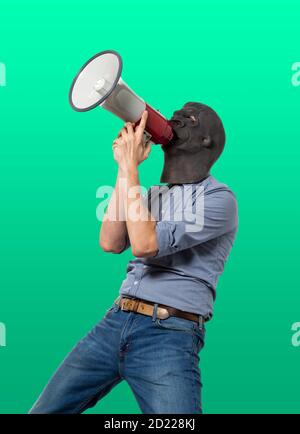 Homme dans le masque de gorille criant sur le mégaphone. Découpe isolée sur fond vert. Trois quarts de longueur. Banque D'Images