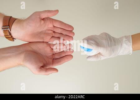 Vue du dessus des mains des femmes en gants de caoutchouc blanc désinfectant mains de sexe masculin avec désinfectant Banque D'Images