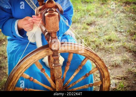 Distaff crée un filetage à partir d'une broche. Roue qui tourne à la main dans la nature, gros plan. Banque D'Images