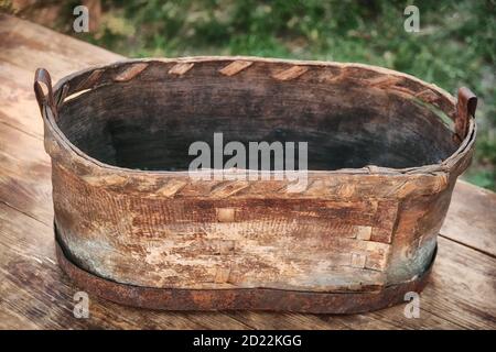 Une ancienne dépression faite de l'écorce d'un arbre. Bain de toilette vintage tissé en bois, avec un rebord en métal au fond. Banque D'Images