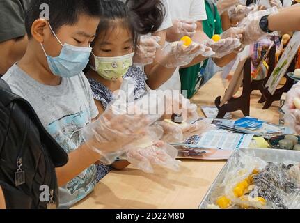 Pékin, province chinoise de Guangdong. 1er octobre 2020. Les touristes essaient de faire des gâteaux de lune dans une rue commerciale de Guangzhou, dans la province de Guangdong, au sud de la Chine, le 1er octobre 2020. Les habitants de toute la Chine apprécient diverses spécialités pendant la fête nationale et les fêtes de la mi-automne. Credit: Liu Dawei/Xinhua/Alay Live News Banque D'Images