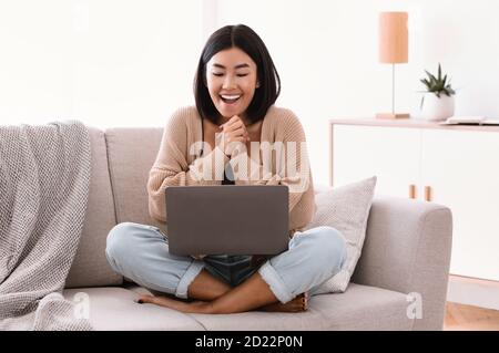 Jeune femme excitée se sentant extatique à l'aide d'un ordinateur portable Banque D'Images