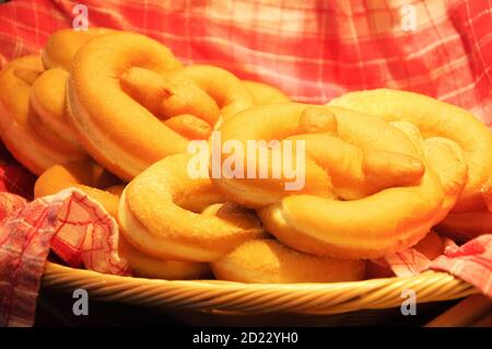 Beignets de bretzel doux sur une serviette à carreaux dans un panier en osier. Sélection de la mise au point sur le textile torsadé. Photo en tons. Banque D'Images