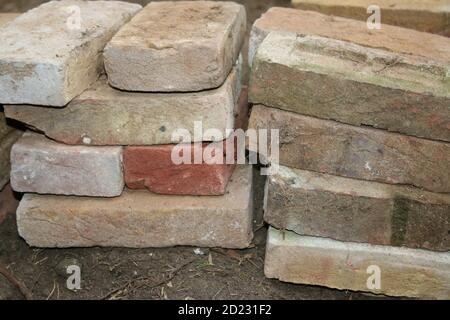 Gros plan de pile de briques anciennes en argile récupérées, chaque rectangle oblong fait à la main et récupéré de la construction à réutiliser pour poser le chemin de jardin à travers la pelouse Banque D'Images