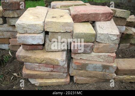 Gros plan de pile de briques anciennes en argile récupérées, chaque rectangle oblong fait à la main et récupéré de la construction à réutiliser pour poser le chemin de jardin à travers la pelouse Banque D'Images