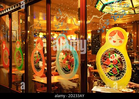 PARIS, FRANCE - 27 DÉCEMBRE 2015 : café parisien en vitrine décoré pour Noël avec des poupées de matryoshka et des flocons de neige colorés. Banque D'Images