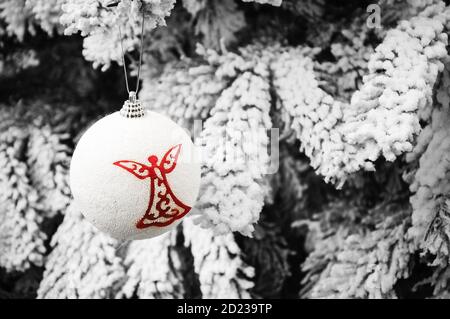 Boule vintage avec silhouette d'ange accrochée à l'arbre de Noël recouvert de neige. Carte de Noël vintage. Mise au point sélective. Photo en tons. Banque D'Images