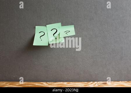 Papier pour notes adhésives avec point d'interrogation sur le mur gris. Réflexion, solution, entreprise, concept d'idée Banque D'Images