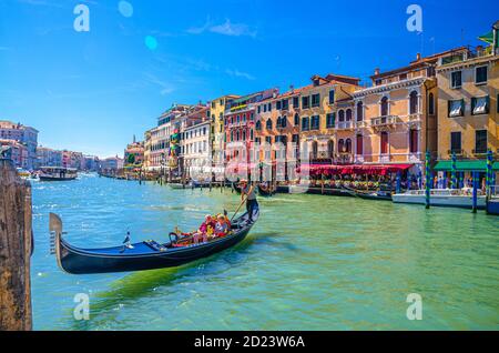 Venise, Italie, 13 septembre 2019 : gondolier et touristes en gondole bateau traditionnel naviguant sur l'eau du Grand Canal avec architecture vénitienne typique bâtiments colorés arrière-plan Banque D'Images