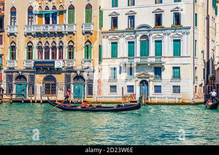 Venise, Italie, 13 septembre 2019 : gondolier et touristes en gondole bateau traditionnel naviguant sur l'eau du Grand Canal avec architecture vénitienne typique bâtiments colorés arrière-plan Banque D'Images
