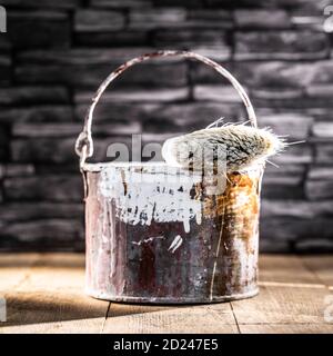 Peindre le seau en étain avec de la peinture rouge et blanche ancien pinceau Banque D'Images