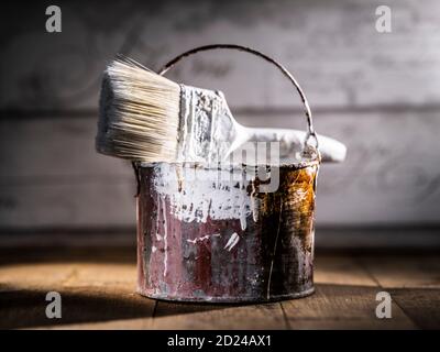 Peindre le seau en étain avec de la peinture rouge et blanche ancien pinceau Banque D'Images