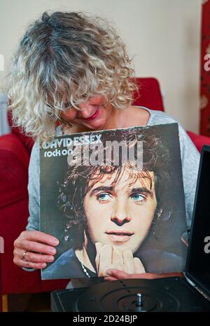 Femme d'âge moyen avec un vieux exemplaire de David Essex Album LP Rock on publié en 1973 par Columbia Records Banque D'Images