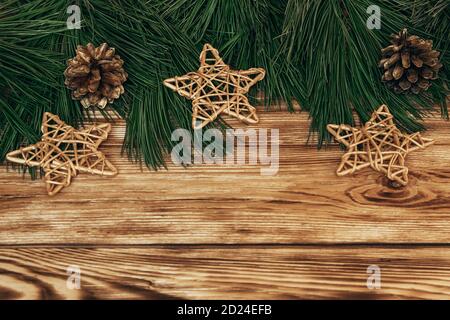 Branches de sapin avec étoiles en osier doré et cônes sur fond de bois. Noël, composition du nouvel an avec espace de texte. Flat lay, vue de dessus Banque D'Images