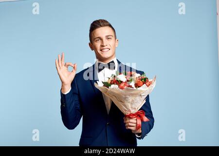 homme romantique avec un bouquet de fleurs et dans un noeud papillon sur fond bleu vue rognée Banque D'Images