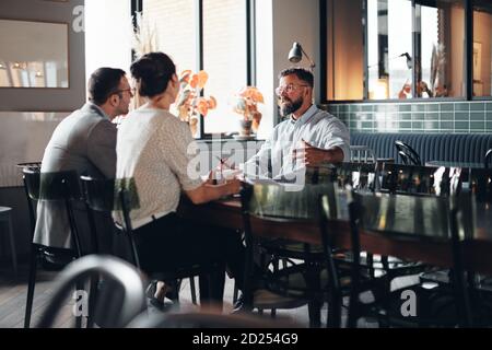 Manager parlant lors d'une réunion informelle avec son personnel café dans le salon d'un bureau Banque D'Images