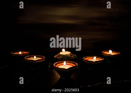 Happy Diwali - Clay Diya lampes allumées pendant Dipavali, festival hindou des lumières célébration. Lampe à huile traditionnelle colorée diya sur fond sombre. Copier Banque D'Images