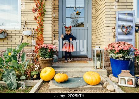 Jeune fille mignonne sur le porche de la maison de campagne avec des citrouilles en chapeaux de costomer. Joyeux halloween. Halloween enfants. Banque D'Images