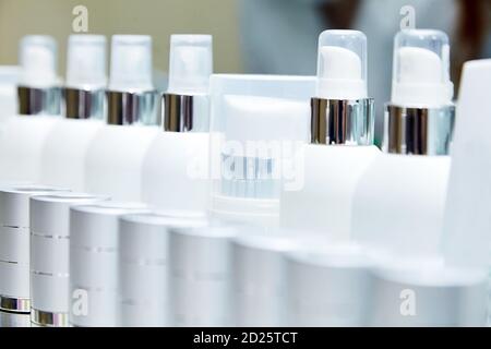 Rangée de bouteilles blanches vierges avec produits cosmétiques. Crèmes hydratantes et autres moyens pour les soins de la peau. Vitrine avec cosmétiques Banque D'Images