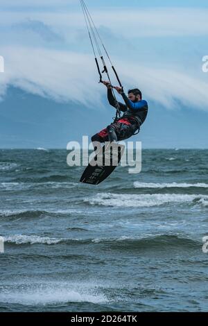 Un kitesurfer se délaisse des vagues à Newborough, Anglesey Banque D'Images