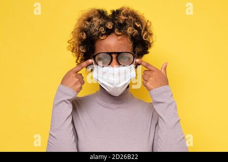 Femme afro-américaine avec des lunettes brumeuses causées par le port d'un Masque de protection COVID Banque D'Images