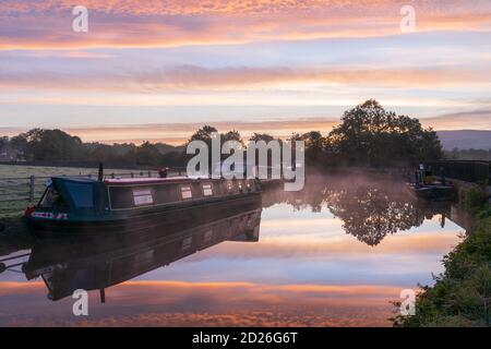 Un superbe lever de soleil au-dessus du canal de Leeds et Liverpool à Skipton, dans le parc national de Yorkshire Dales, tandis que les bateaux-canaux flottent sur le miroir de l'eau calme. Banque D'Images