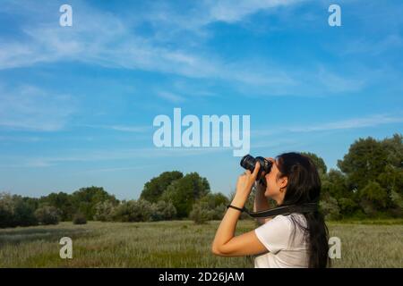 Une jeune femme photographie le ciel bleu avec un appareil photo reflex. Espace de copie, concept de paysage de photographie. Banque D'Images