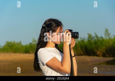 La jeune femme photographie le paysage un jour d'été. Profession photographique. Superbe effet bokeh, mise au point sélective. Banque D'Images